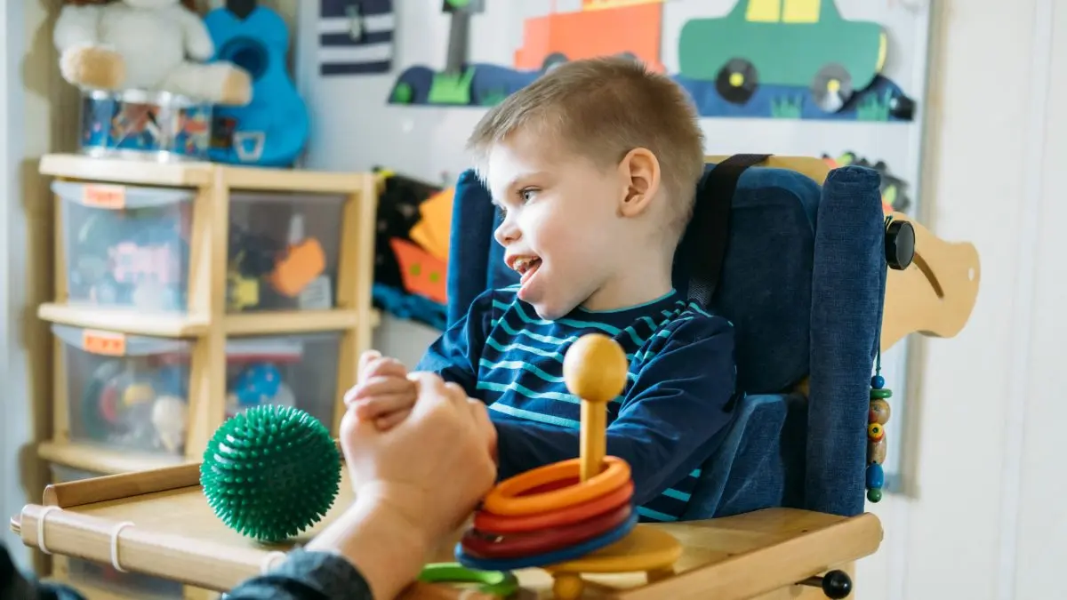 Niño con parálisis cerebral en una trona.